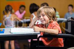 Boy on wheelchair writing on book