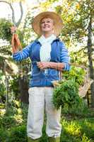 Happy gardener standing with fresh vegetables at garden