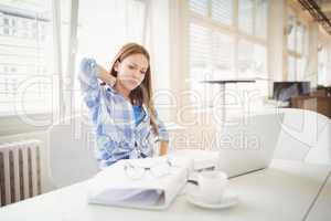Tired businesswoman sitting at desk in creative office