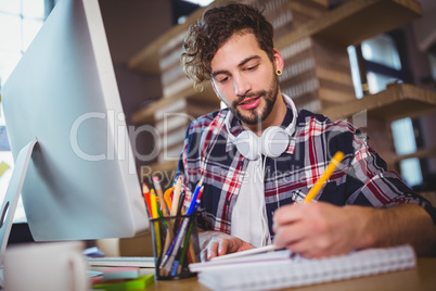 Creative businessman writing in spiral notebook