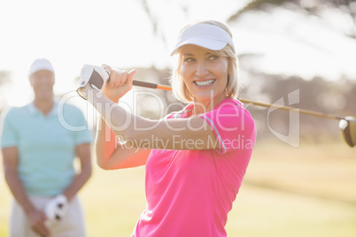 Confident mature woman carrying golf club by man