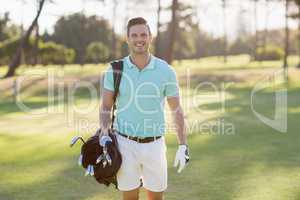 Portrait of smiling young man carrying golf bag