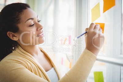 Businesswoman smiling while writing on adhesive note
