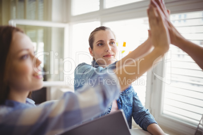 Female coworkers giving high-five in creative office