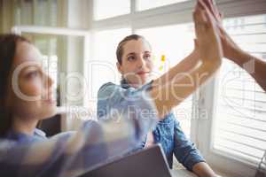 Female coworkers giving high-five in creative office