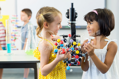 Girls looking at each other while holding DNA model