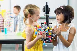 Girls looking at each other while holding DNA model