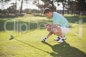 Side view of young man placing golf ball on tee