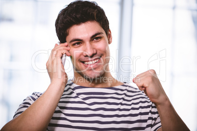 Happy executive listening to cellphone while punching in air at