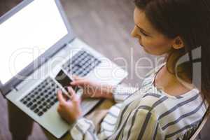High angle view of businesswoman using cellphone over laptop at