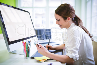 Graphic designer holding phone while working