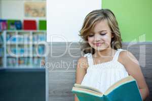 Smiling girl reading book in school library