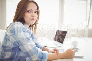 Young businesswoman with laptop and digital tablet in office