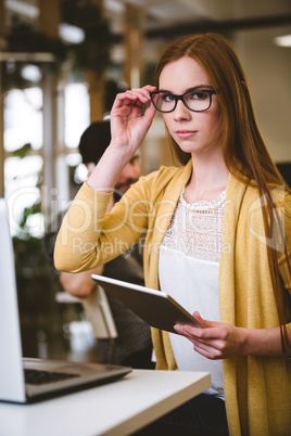 Confident businesswoman adjusting eyeglasses