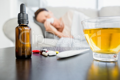 Medicines and herbal tea by thermometer on table