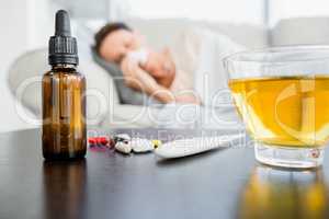 Medicines and herbal tea by thermometer on table