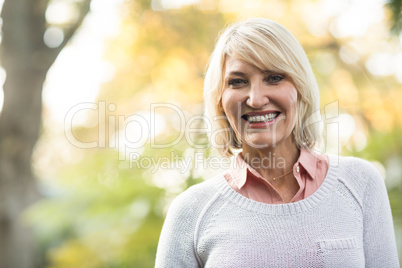 Mature woman smiling while standing in forest