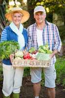 Portrait of happy couple with fresh vegetables at garden
