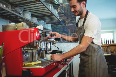 Happy barista using coffee maker at cafe