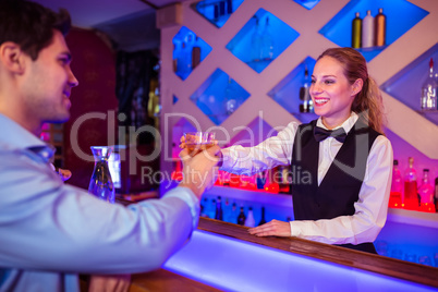 Barmaid smiling while serving drink to male costumer