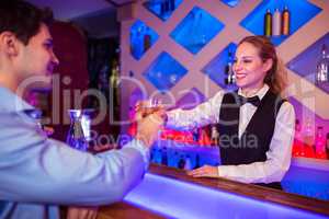 Barmaid smiling while serving drink to male costumer