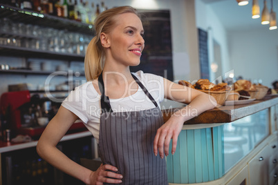 Happy female barista standing at counter in coffee shop