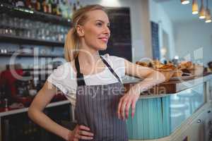 Happy female barista standing at counter in coffee shop