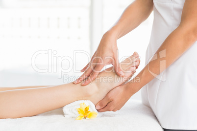 Midsection of masseur giving foot massage to woman