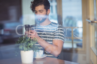 Handsome man typing on cellphone at cafe