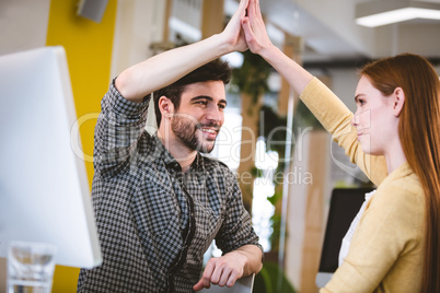 Smiling businessman giving high-five to female coworker