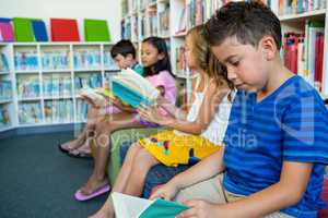 Students reading books while sitting on seats at school library