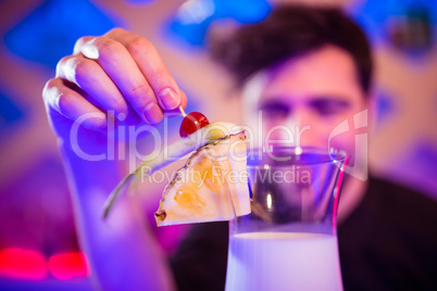 Bartender keeping fruits on cocktail glass