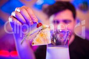 Bartender keeping fruits on cocktail glass