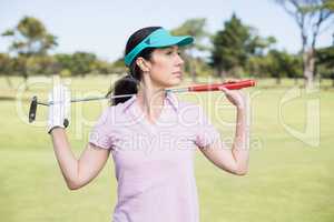 Confident woman carrying golf club