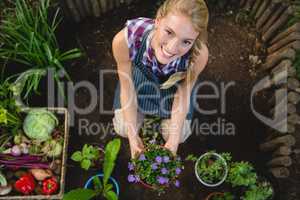 Portrait of happy gardener with potted plant at garden