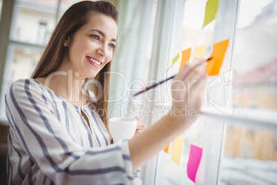 Businesswoman writing on adhesive notes in creative office