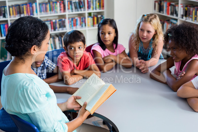 Teacher reading book at children look at her