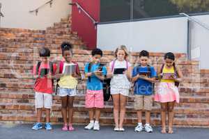 Full length of students using digital tablets