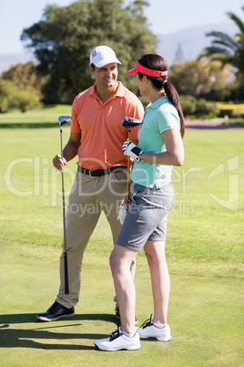 Cheerful couple holding golf clubs