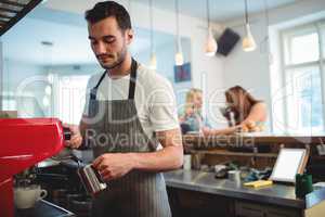 Young barista pouring coffee at cafe