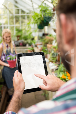 Cropped image of gardener using tablet at greenhouse