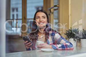 Happy beautiful woman with cellphone at cafe