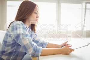 Young businesswoman holding digital tablet in creative office