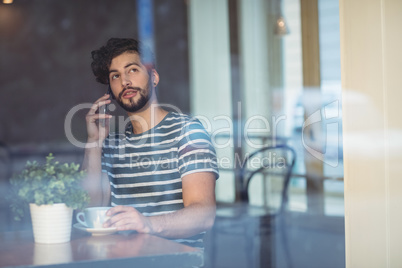 Handsome customer talking on cellphone at cafe Handsome customer talking on cellphone at cafe