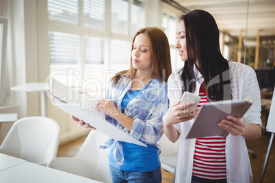 Female colleagues discussing with files in creative office