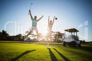 Full length of golf player couple with arms raised