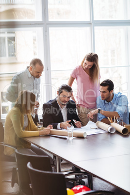 Business people with blueprint in meeting room