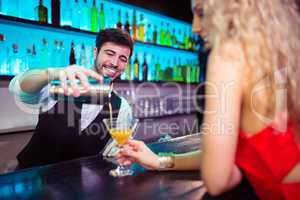 Barkeeper serving cocktail to young woman
