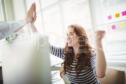 Excited coworkers giving high-five at creative office