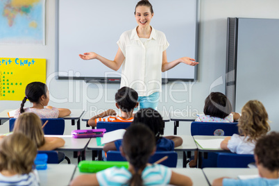 Teacher with arms outstretched in classroom